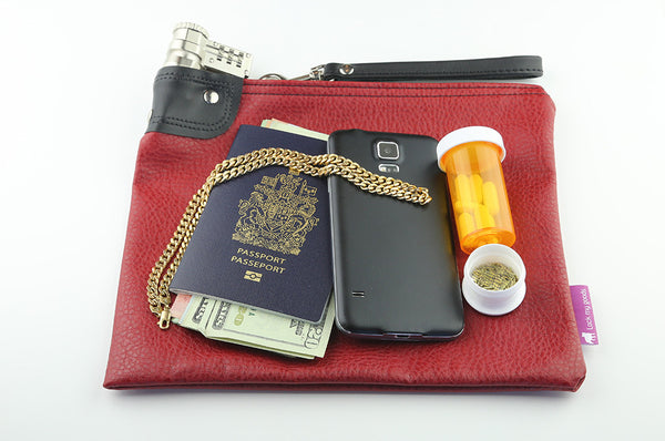 Cranberry red, locking bag with combination, shown with passport, smart phone, jewelry, cash and medication. 