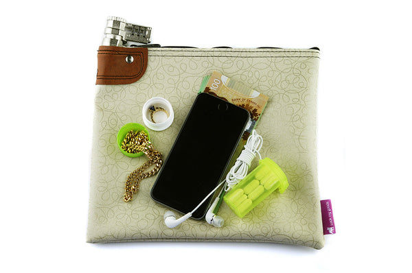 Creme coloured locking bag shown with smart phone, jewelry, medication and cash. 